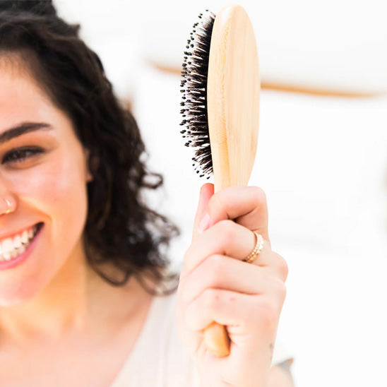 femme souriant avec brosse a cheveux en poil de sanglier